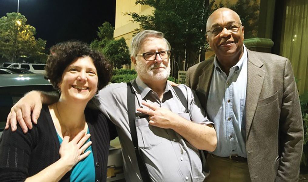 Naomi Nelson, Bruce Hartford, and Courtland Cox gather together for a photo. Bruce has his arm around Naomi’s shoulder.