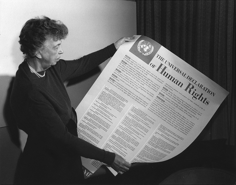 Black and white photo of Eleanor Roosevelt holding a poster of the Universal Declaration of Human Rights
