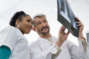 Two radiologic technologists consult with each other about an X-ray image.