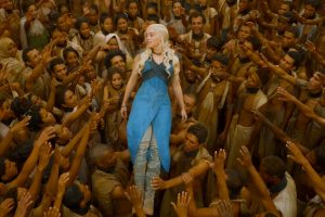 Daenearys Targaryen, a young white woman from Game of Thrones, is being carried by a crowd of darker-skinned people.