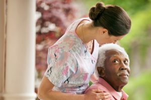 A healthcare professional assists an elderly patient in a wheelchair.