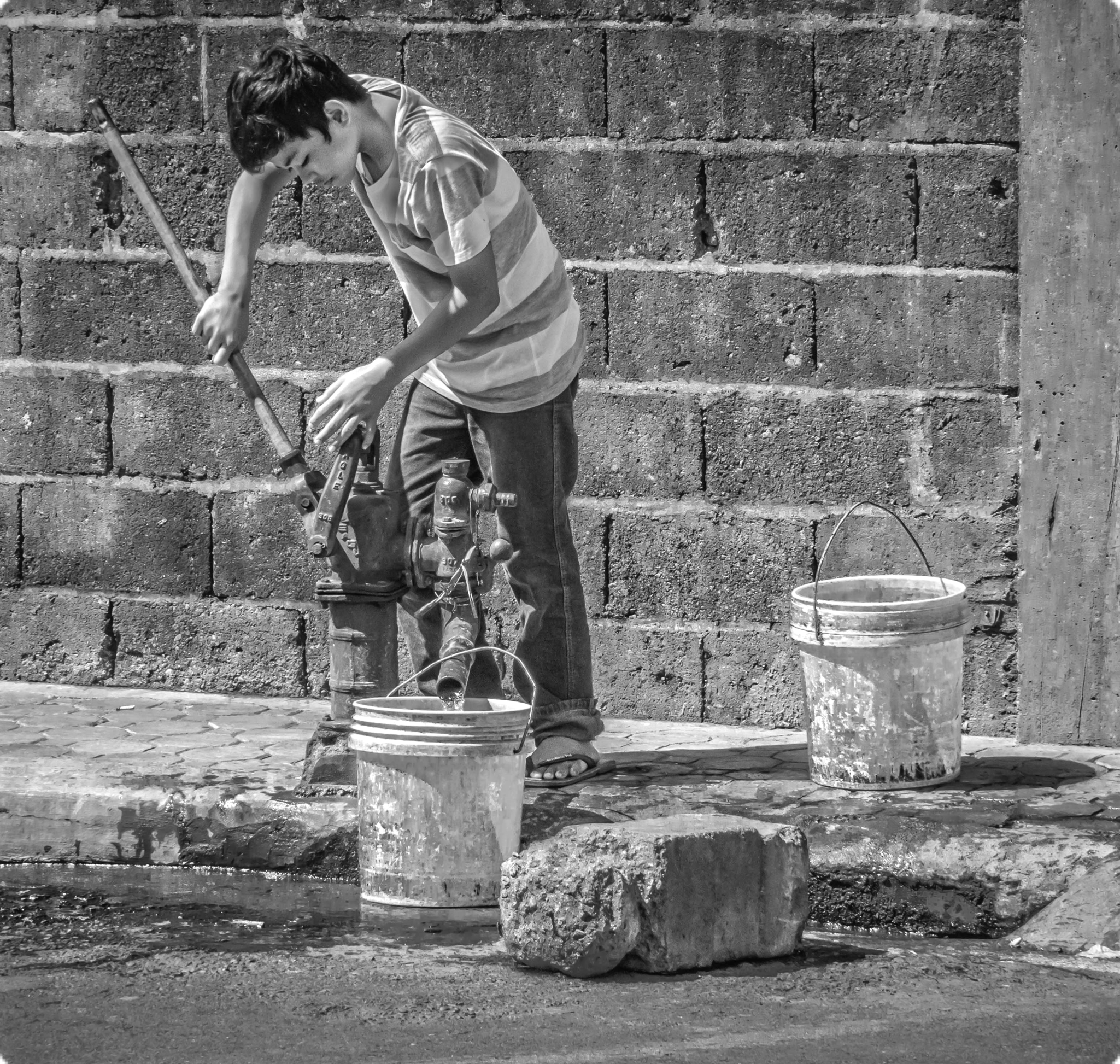 Boy acquiring water from a well.