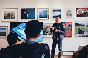 Man Beside Flat Screen Television With Photos On Wall in Background