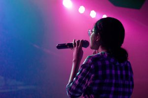 person holding microphone with pink and blue lights around them