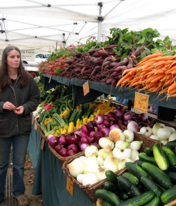 A woman looks on at the large two-tier display of produce underneath an expansive pop-up tent.