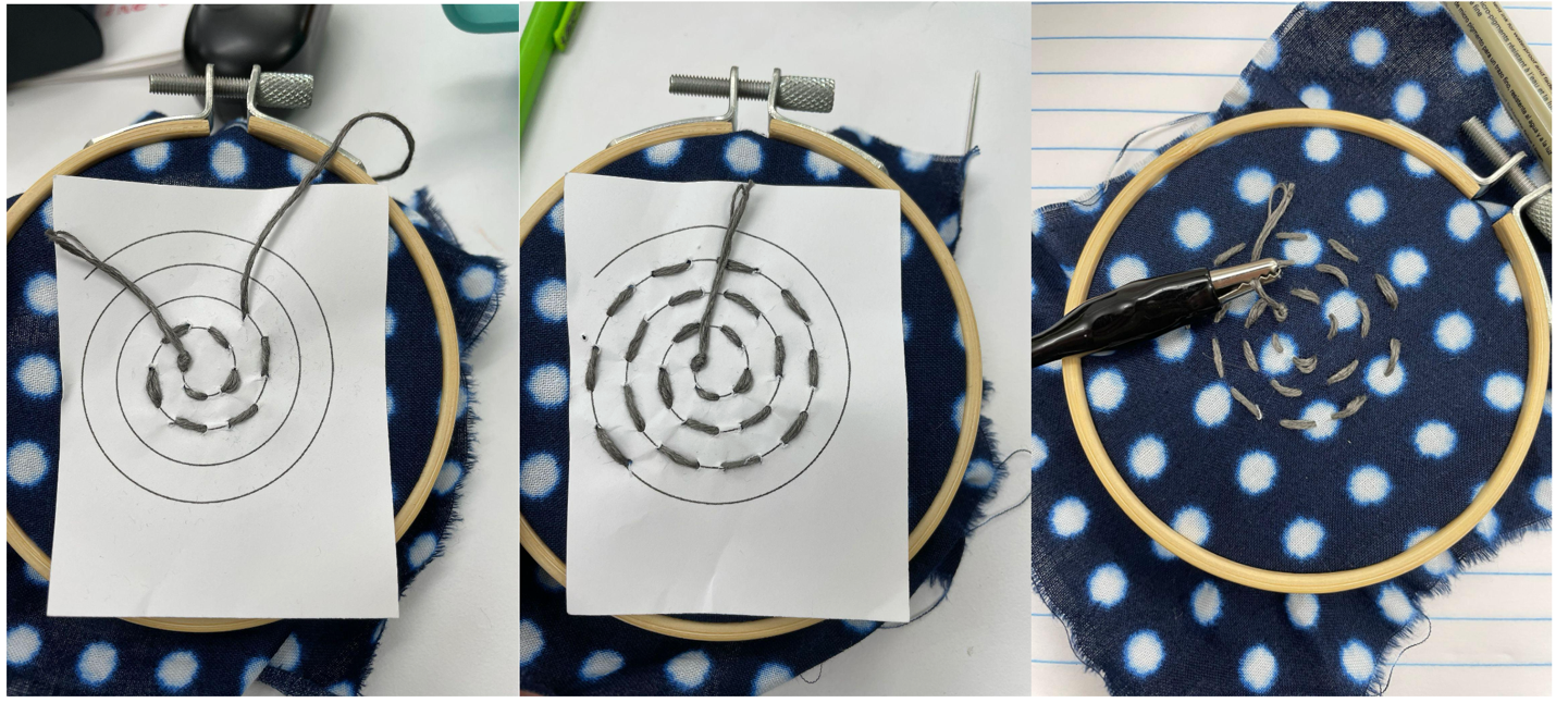 Three photos of the same embroidery hoop with blue and black fabric on it. In the first photo, a piece of paper with a spiral pattern is on the embroidery hoop, and it is partially stitched. In the second photo, the spiral pattern on the piece of paper has been entirely stitched. In the third photo, the paper pattern is removed, and an alligator clip is attached to the end of the thread in the center of the spiral.