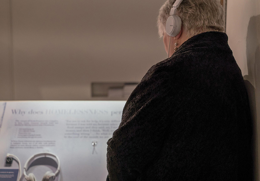 Silver-haired woman listens to story using headphones.