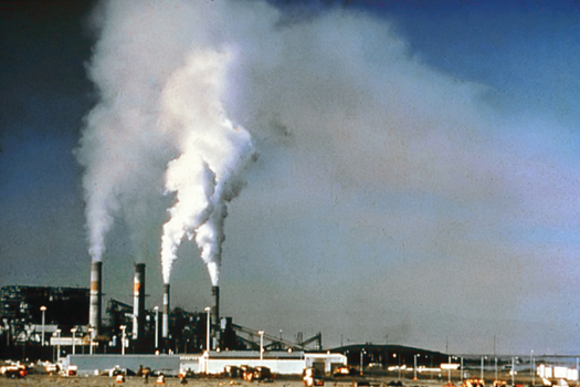 An image of a power plant with large columns of smoke billowing out of its four towers.