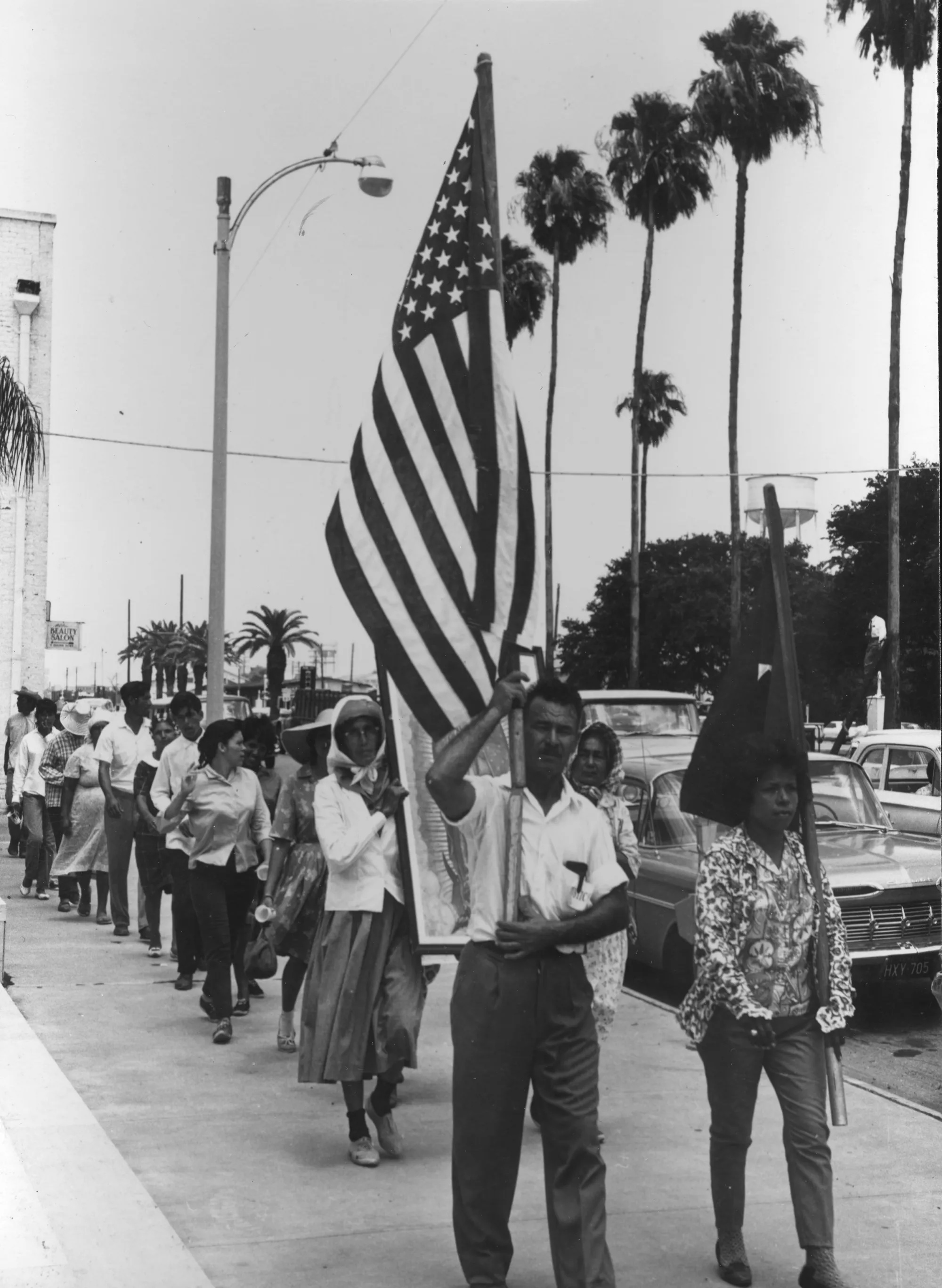 Farm workers marching through a town carrying flags