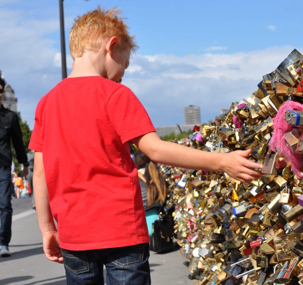 boy looking at locks on the fence