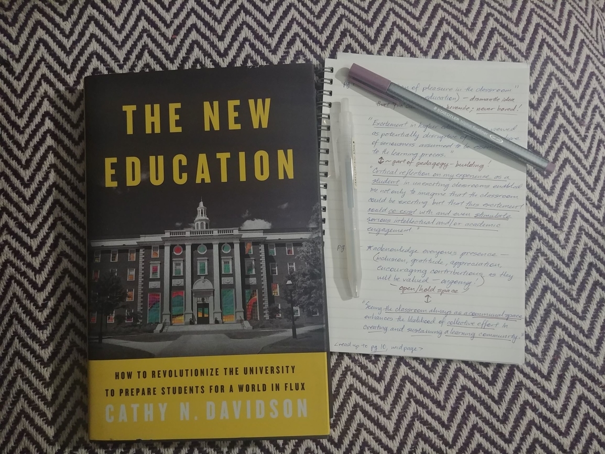 Photo of a copy of Cathy N. Davidson's book, The New Education, and a notebook containing quotes from bell hooks' book, Teaching to Transgress. Two pens scattered on notebook.