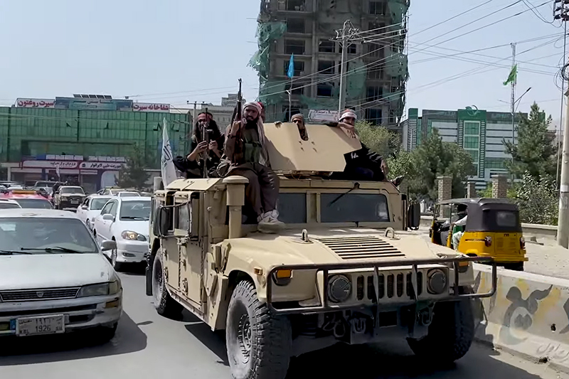 Taliban fighters ride a captured Humvee after the fall of Kabul