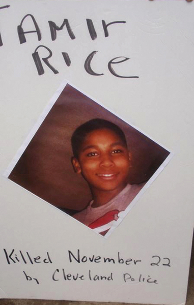 White poster with large picture of Tamir Rice at the center. Above the picture, “Tamir Rice” is written and below it reads “Killed November 22 by Cleveland Police.”