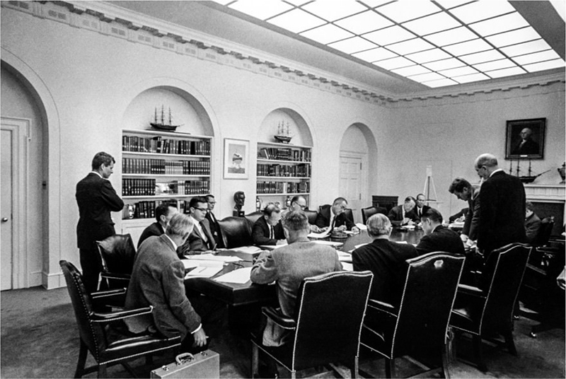 Black and white photo of a group of people sitting around a table
