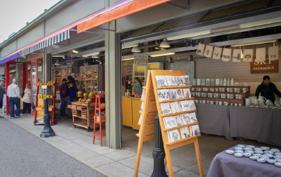 Vendor displays extend into the street. Shows an easel with art on it.