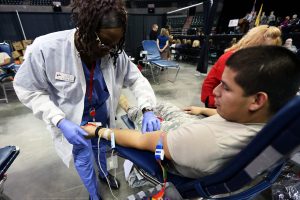 A phlebotomist prepares to draw blood from a patient.