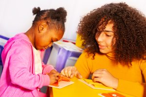 A woman watching as a child draws.