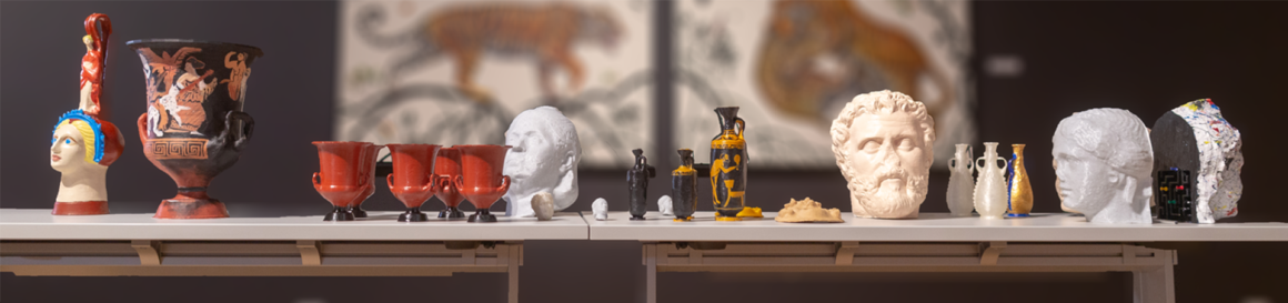 Landscape view of a table display presenting multiple 3D printed versions of antiquities within the Lowe Art Museum.