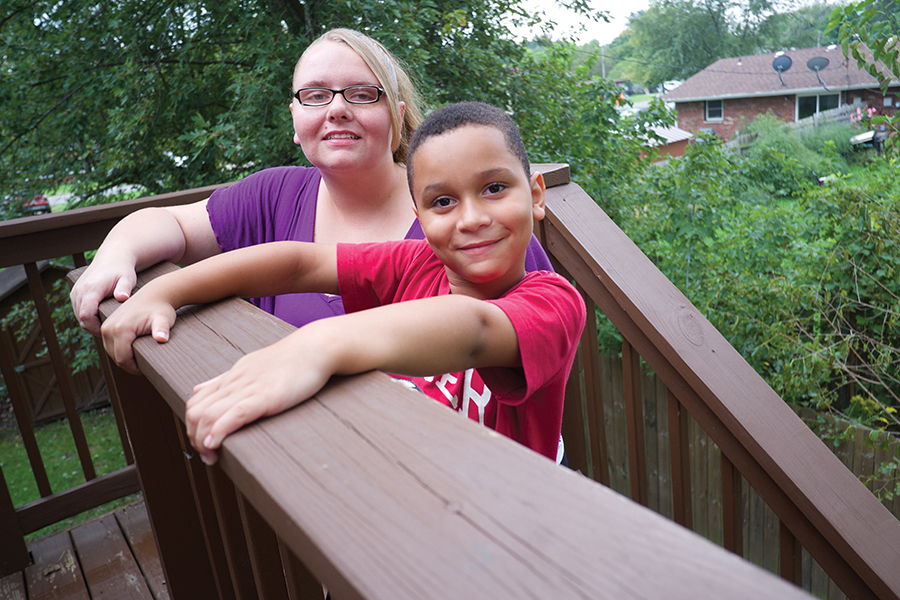 Smiling woman with glasses next to young, smiling son.