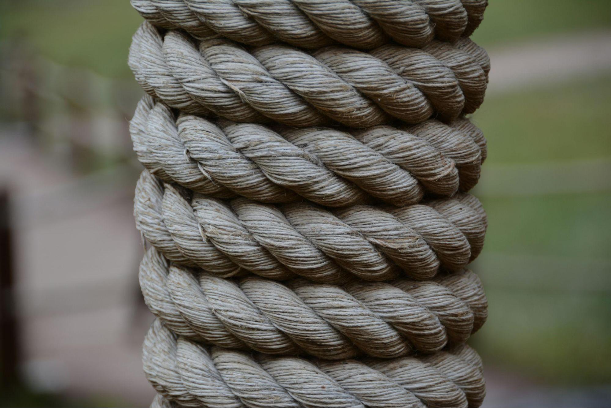 A close-up of thick, coiled hemp rope, tightly wound in even layers, suggesting strength, structure, and tension.