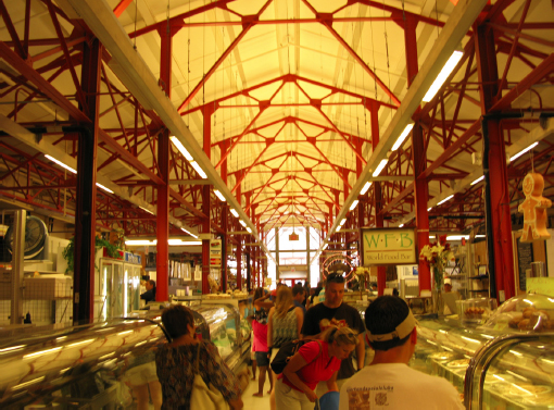 Inside Findlay market. Distinctive Tuscan red Fink trusses line the ceiling with patrons milling around below.