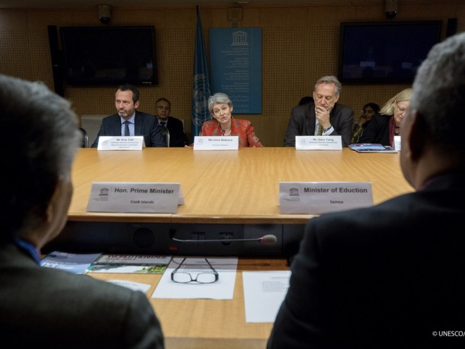 view from behind two people sitting at a board room table, across from 4 white people: 2 men and 2 women