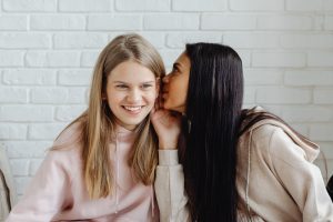 a woman whispering something to another woman