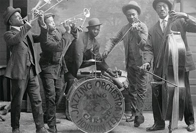 A photograph shows a group of black jazz musicians playing their instruments. A drum reads “Jazzing Orchestra / King and Carter / Houston Tex.”