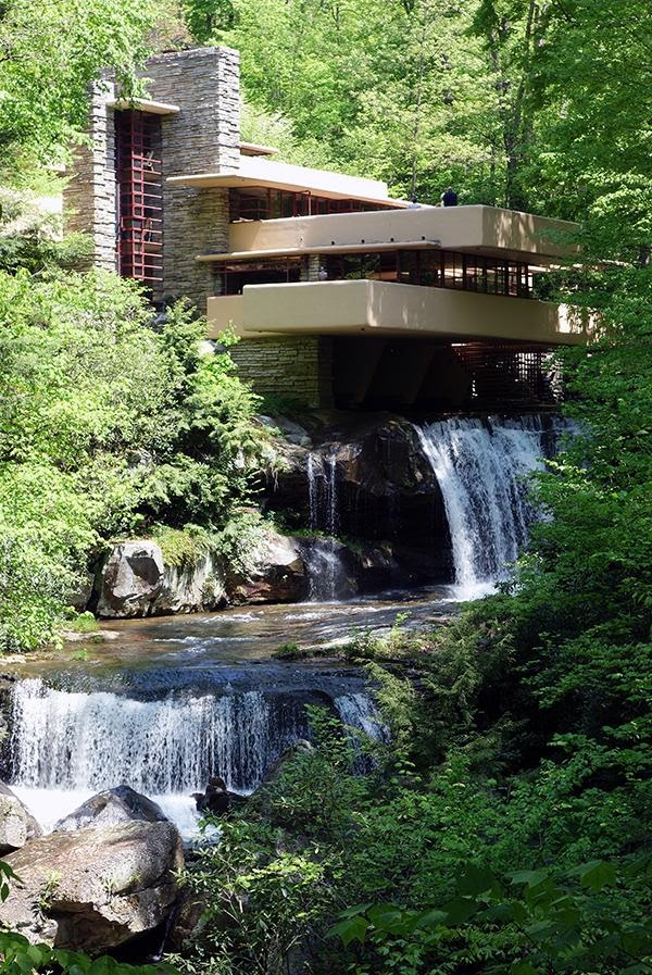 Full page photograph of Fallingwater. A home built into a waterfall surrounded by trees. 