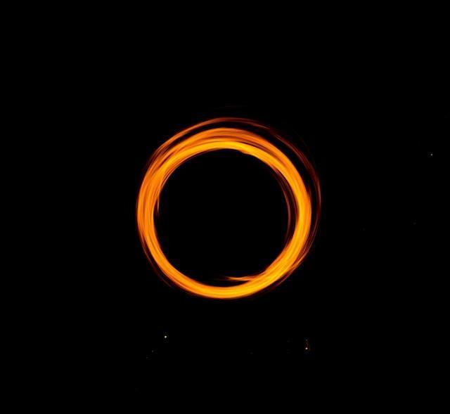 A glowing orange ring of light against a black background, resembling a flaming circle or spinning light effect.