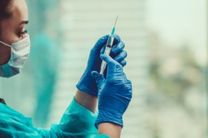 Health professional prepares a needle containing medicine.