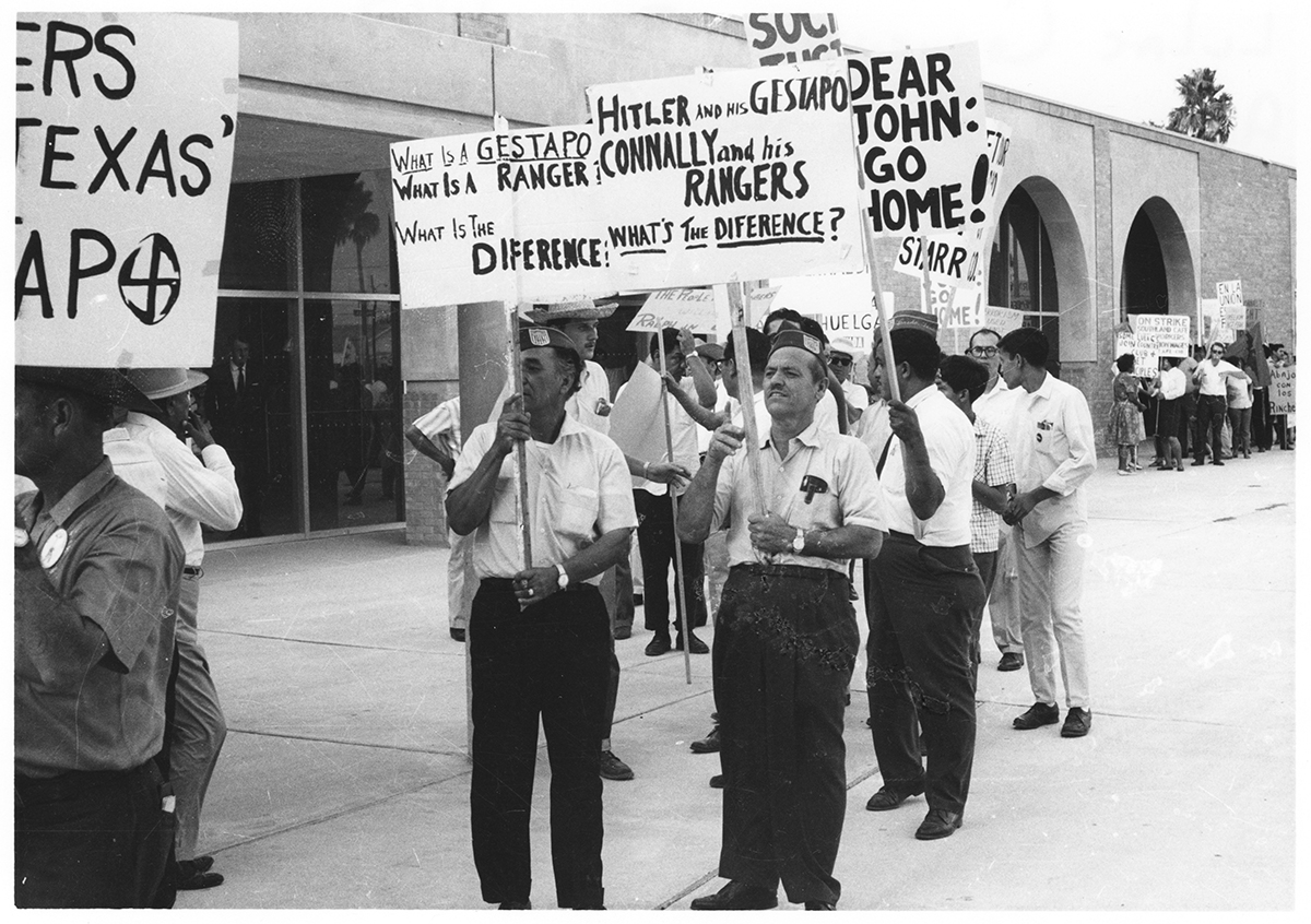 Members of the American GI Forum picket while carrying signs comparing Texas Rangers to the Gestapo of Nazi Germany.