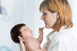 A nurse midwife holding an infant.