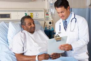 A photo depicting a doctor consulting with a patient, who is in a hospital bed.