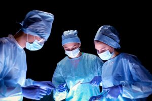 A team of physicians and surgeons perform an operation.