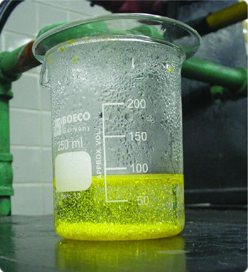 Beaker showing the formation of a bright yellow solid in a precipitation reaction.
