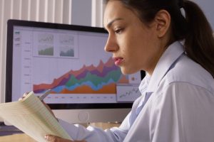 A business woman sits at a desk reading paperwork.
