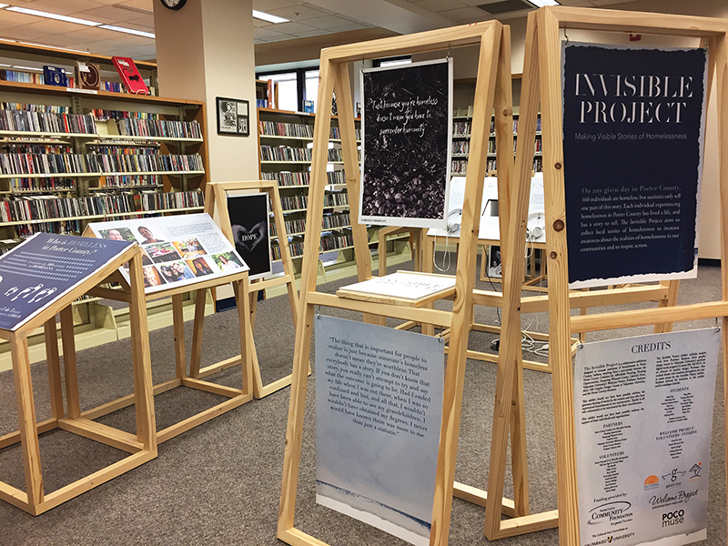Wooden structures of the Invisible Project exhibit installed in a library.