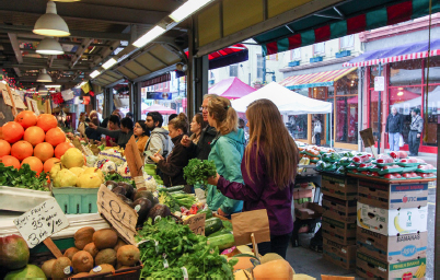 People lining up to buy produce from the vendor displays.