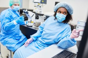 Two technicians in the laboratory staring at a computer.