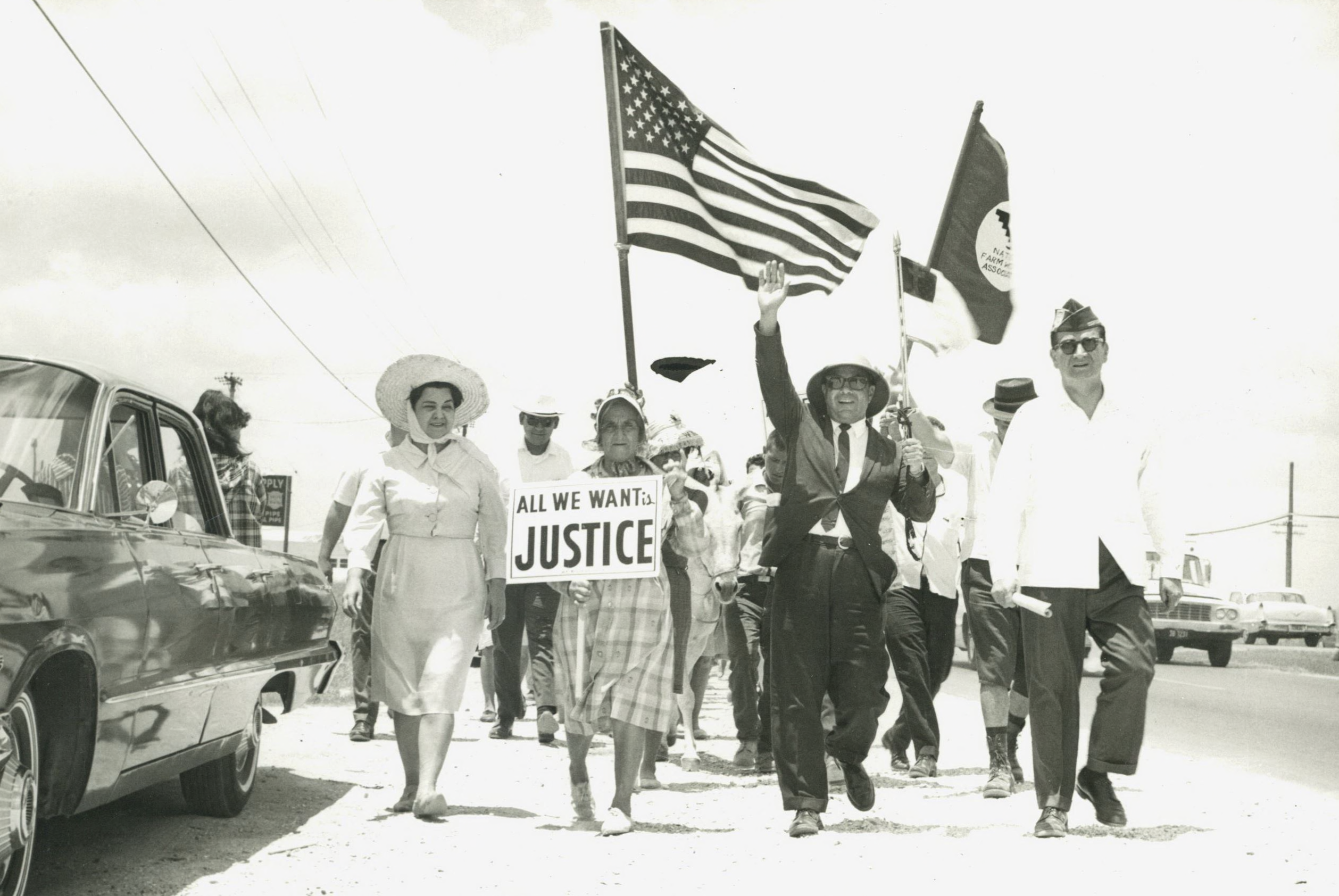 Hector P. Garcia in his American GI Forum hat marching with farm workers, carrying flags