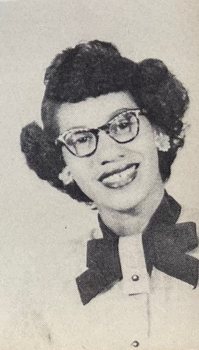A young African American woman wearing glasses and a bowtie in a yearbook photograph