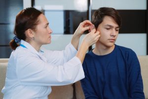An audiologist fits a patient for a hearing aid.