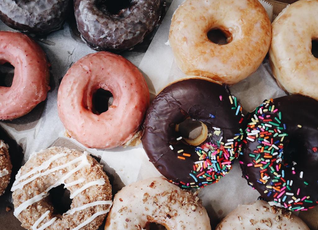 A variety of 12 donuts lined up in three rows of four donuts