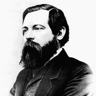 A gray-scale photo portrait of Friedrich Engels. He has a very large, but neatly-manicured beard. His hair is also neatly combed. He is wearing a suit and facing to the left.  Year: 1868. Photographer: George Lester. Source: https://en.wikipedia.org/wiki/Image:Engelss56fe1.jpg