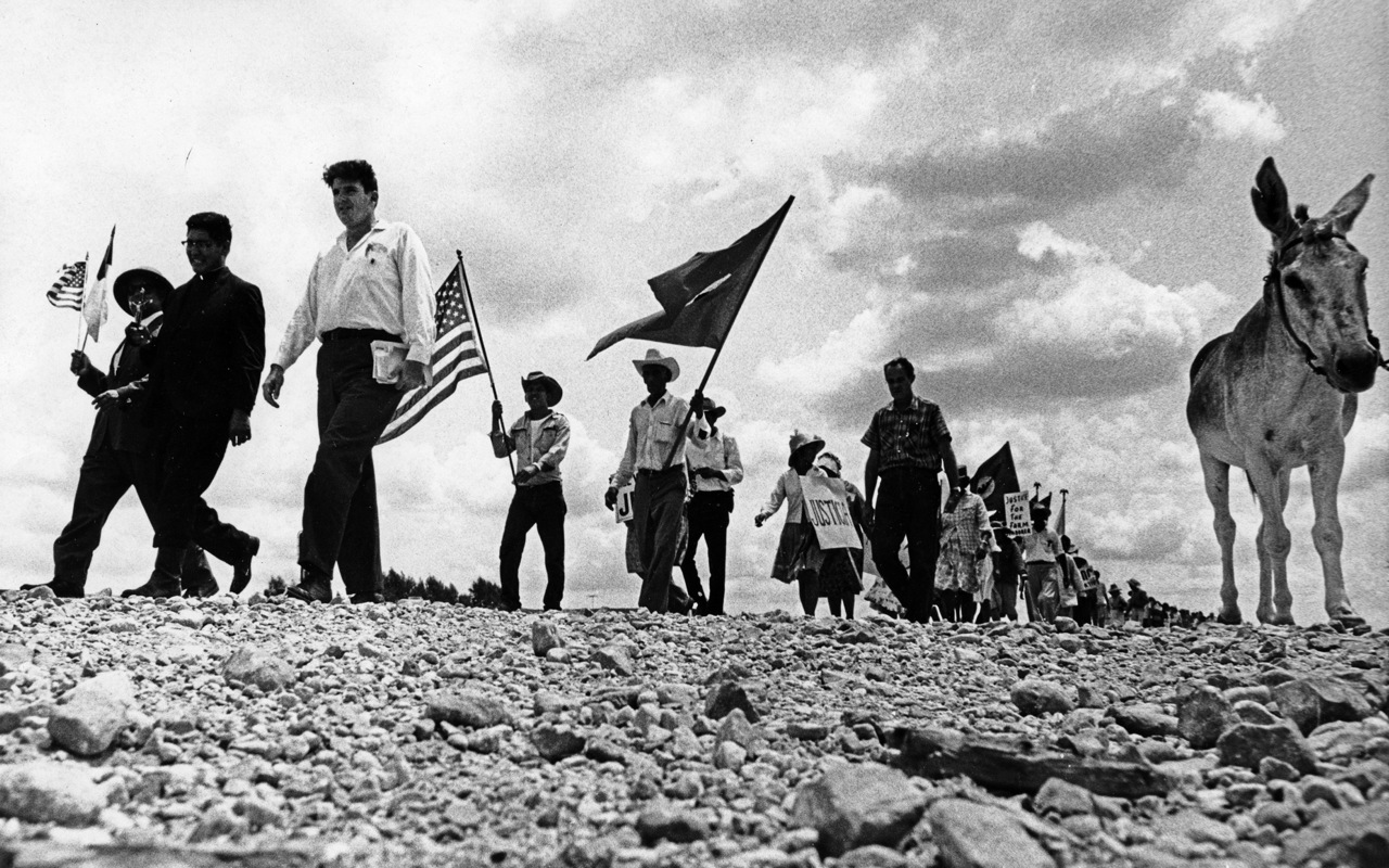 Farm workers marching while carrying signs and flags