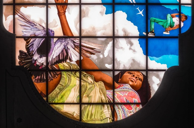Close up of a stained glass windows on the ceiling of the Moynihan train station, featuring a Black girl, a pigeon, and a Black boy in active stances.