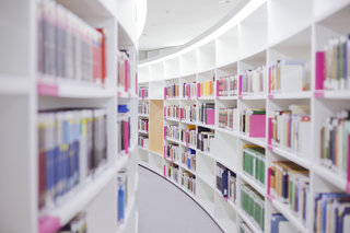 A well-lit library with white shelves and colorful books. The path curves slightly, making for an inviting composition.
