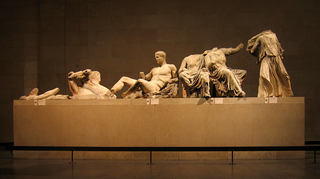 Left section of the east pediment of the Parthenon. Helios and his chariot are emerging, while Dionysos is reclining. There are several female goddesses depicted as well, including Demeter, Kore and Artemis, though the exact identities of the goddesses are unknown because their heads do not survive to the present day.