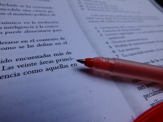 A red pen rests atop a page of text written in Spanish.